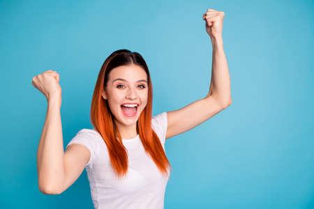 Portrait charming  sweet ecstatic satisfied lady youth celebration lottery open mouth raise fists weekend holiday aim goals shout yeah content  isolated dressed fashionable  clothes blue backgroundの写真素材