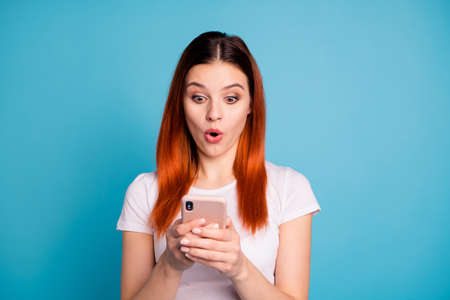 Close-up portrait of her she nice attractive winsome lovely cheerful cheery girlish lady wearing white t-shirt using device gadget browsing isolated on bright vivid shine blue backgroundの写真素材