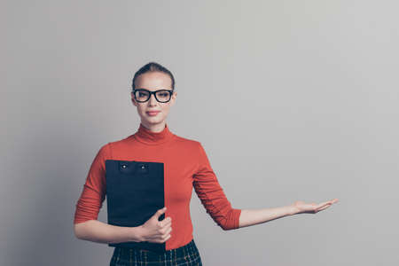Portrait of her she nice pretty lovely winsome attractive cute sweet girl holding in hand clipboard copy empty blank space isolated over gray pastel backgroundの写真素材