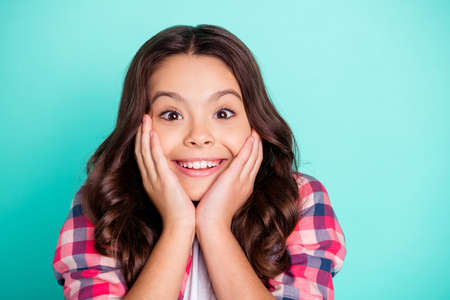 Close-up portrait of nice attractive lovely sweet winsome dreamy cheery cheerful wavy-haired pre-teen girl wearing checked shirt enjoying good news isolated on bright vivid shine blue backgroundの写真素材
