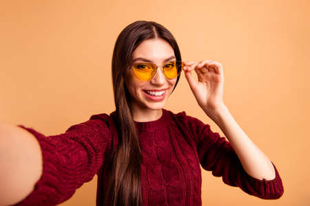 Beautiful woman taking self photograph on beige pastel background
