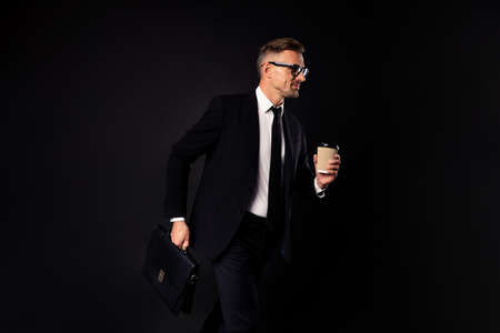 Portrait of his he nice classy chic attractive content leader partner professional banker real estate sales ceo boss chief going to office holding in hand latte isolated over black backgroundの写真素材