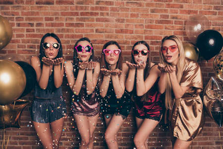 Portrait of nice cool company attractive sweet fascinating winsome lovely lovable gorgeous flirty cheerful ladies having fun sending you kiss flirt glow glossy isolated over industrial brick wallの写真素材