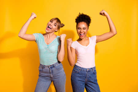 Close up photo beautiful wild roar she her lady hooray hands arms fists raise yell amazed different nationalities celebrate wear casual white striped t-shirt clothes isolated yellow bright backgroundの写真素材