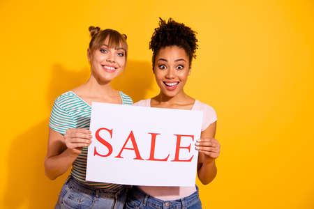 Portrait of nice cute funny funky lady hold hand paper sale enjoy bun weekends free time wavy curly hairdo top-knot style stylish trendy t-shirt isolated on yellow backgroundの写真素材