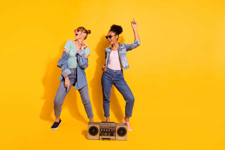 Full length body size view photo cheerful funky student people retro sing summer journey travel sea raise hand denim wavy curly top-knot bun beautiful trendy stylish t-shirt isolated yellow backgroundの写真素材