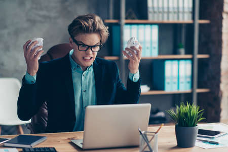 Portrait depressed frustrated guy hold hand crazy paper use pc wrong task solution decide choose choice start-up scream negative reaction sit table desk black blazers interior industrial.の写真素材