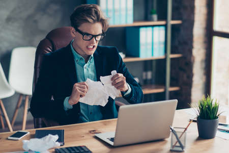 Portrait negative depressed frustrated guy hold hand paper work shred want shout sheets development use user laptop wrong decision solution decide choose choice stylish trendy suit interior industrial.の写真素材