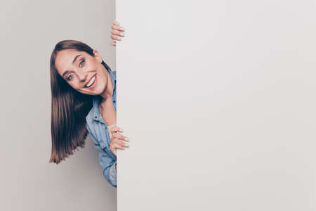 Portrait of nice-looking attractive lovely sine cheerful cheery straight-haired lady holding hands behind big large promotion ad advert isolated over light white gray background.の写真素材