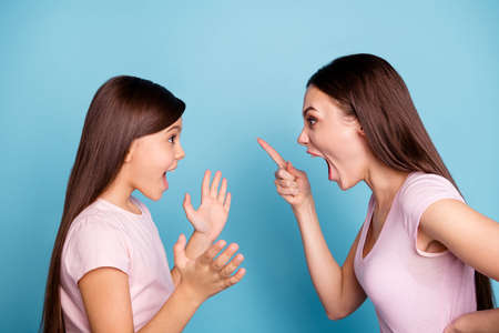 Close-up profile side view portrait of two nice attractive fury furious annoyed irritated straight-haired girls having fight disagreement isolated on bright vivid shine green blue turquoise backgroundの写真素材