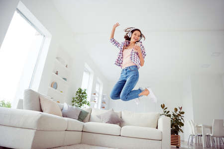 Full length body size view low angle view photo funny funky teen teenager hold hand device rhythm melody singer party beautiful wavy curly haircut trendy stylish plaid hipster jeans room apartmentの写真素材