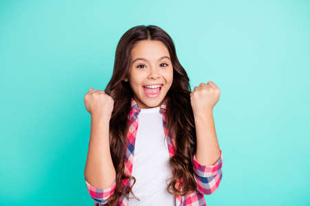 Portrait of cute charming nice girl children raise fists scream get aim gamer lucky fortune goal fan wear plaid fashionable clothes isolated green background.の写真素材