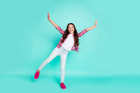 Full length body size view photo pretty cute childish careless lady little cute feel content raise hands arms enjoy free time vacation modern clothing plaid trousers sneakers isolated teal background.の写真素材
