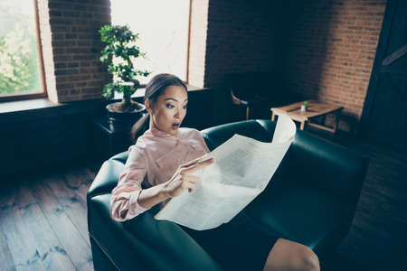 Portrait of her she nice attractive stunned wondered lady experienced expert sitting on comfortable couch reading financial news at modern industrial loft interior style work place stationの写真素材