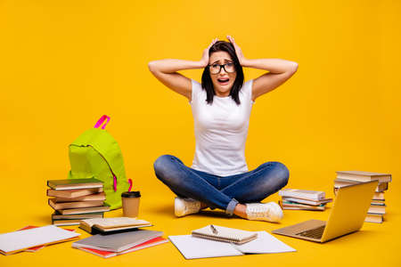 Full length body size photo beautiful she her sit floor hands arms head organizer planner messy urgency homework overworked wear casual white t-shirt jeans denim isolated bright yellow backgroundの写真素材