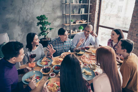 Close up photo communication best festive company social crowd event birthday members funky different race guys glass beverage sit table shirts formal-wear sweater pullover loft room indoorsの写真素材