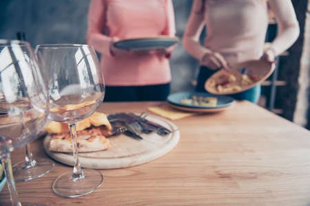 Cropped close up photo two people she her ladies arms hold dirty plates clean wash table holiday dishes kitchen apply forks knifes prepare dining loft room sweet cookies cafe restaurant indoorsの写真素材