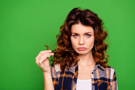 Close-up portrait of her she nice-looking attractive lovely girlish frustrated disappointed wavy-haired lady showing damaged curl end isolated over bright vivid shine green backgroundの写真素材