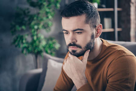 Close-up portrait of his he nice-looking attractive bearded sad minded moody guy spending spare time thinking at industrial loft interior style living-room indoorsの写真素材
