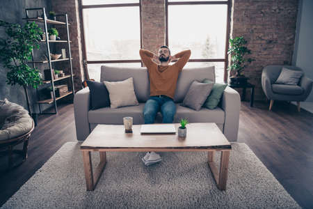 Portrait of his he nice attractive bearded guy sitting on divan closed eyes having rest at industrial loft interior wooden brick style living-room indoorsの写真素材