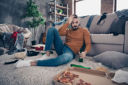 Portrait of astonished cute student touch head forehead hand palm look unbelievable unexpected festival feast sit white sneakers denim jeans orange pullover sweater big roomの写真素材