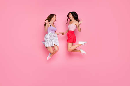 Full length body size view portrait of nice-looking attractive lovely careless carefree cheerful cheery girls having fun time jumping up in air campus isolated over pink pastel backgroundの写真素材