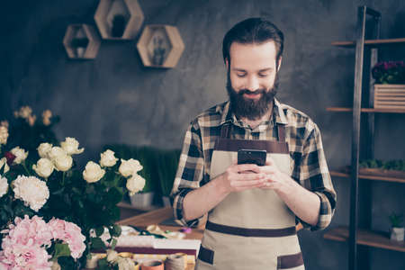 Portrait of handsome stylish trendy nice millennial people small representative hold hand modern technology device blog blogger look news information feel content enjoy dressed plaid shirt greenhouseの写真素材