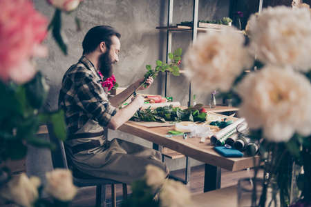 Profile side view photo of focused concentrated handsome person small business representative hold hand natural botanical offer order delivery sit desk table art craft work plaid shirtの写真素材