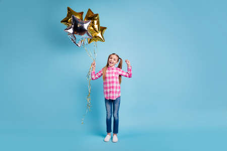 Full length body size photo beautiful she her little hands arms golden silver balloons star shape figure festive gift present wear casual checkered plaid pink shirt isolated bright blue backgroundの写真素材