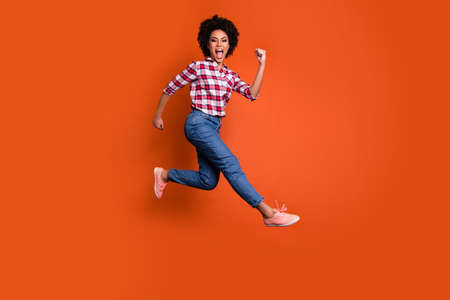 Full length profile photo of jumping high model lady yelling sale discount wear casual pants shirt clothes outfit isolated orange backgroundの写真素材