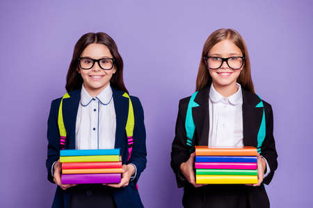Portrait of cute schoolchildren hold hand literature preparation bag backpack, rucksack isolated over purple backgroundの写真素材