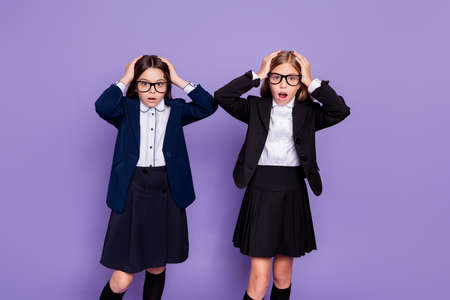 Portrait of frustrated beautiful girls touch hands head negative reaction wear eyeglasses, eyewear jacket isolated over purple violet backgroundの写真素材