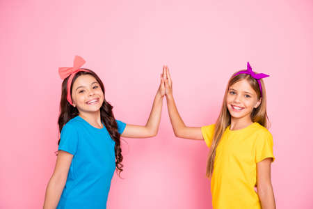 Portrait of two nice-looking attractive charming lovely winsome friendly, cheerful cheery glad pre-teen girls giving five isolated on pink pastel backgroundの写真素材