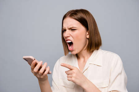 Close up photo furious amazing beautiful she her lady hold hands arms telephone listen unexpected bad news wild roar boyfriend displeased madness wear casual white shirt isolated grey backgroundの写真素材