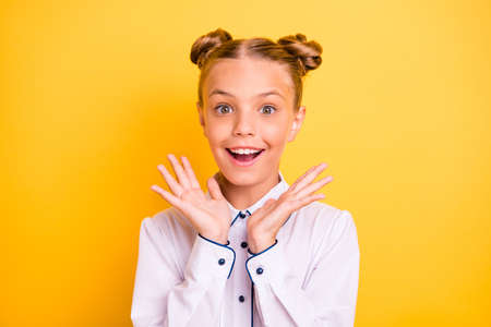 Close-up portrait of her she nice attractive lovely cheerful cheery surprised pre-teen girl wearing white shirt desirable dream satisfaction isolated on bright vivid shine yellow backgroundの写真素材