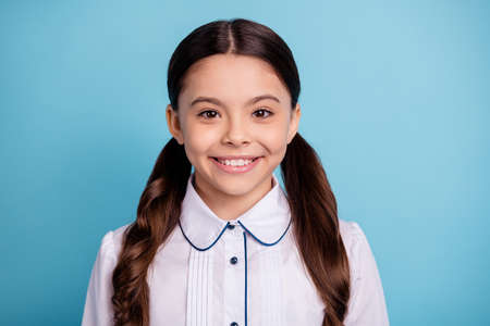 Close up photo of lovely kid looking wear white blouse isolated over blue backgroundの写真素材