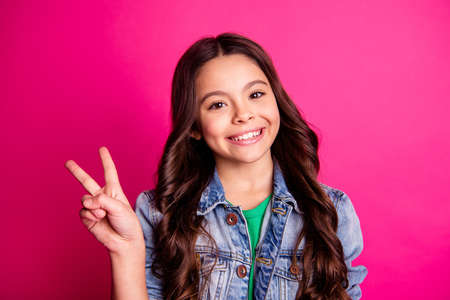 Close up photo little age beautiful she her girl hold arm show v-sign say hi friends relatives positive optimistic wear casual jeans denim jacket isolated pink bright vibrant vivid backgroundの写真素材