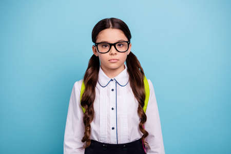 Closeup photo of pretty school lady not smiling return school sorrow bad emotions wear specs white shirt isolated blue backgroundの写真素材