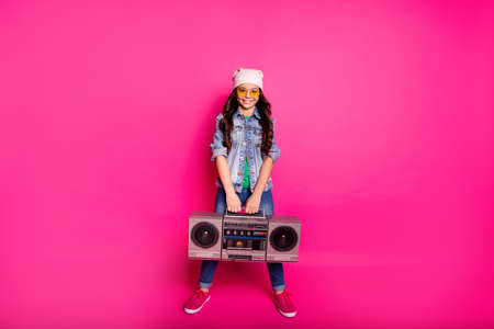 Full length body size photo amazing beautiful little she her curly lady holiday party hands arms old tape audio recorder wear yellow sun specs hat casual jeans denim jacket isolated pink backgroundの写真素材