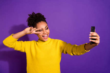 Close-up portrait of nice attractive lovely cheerful cheery positive careless carefree wavy-haired girl taking making selfie showing v-sign isolated over bright vivid shine violet backgroundの写真素材