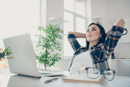 Close up photo of lovely attractive lady touch head hands palms feel satisfied look have thoughts minded wear checkered shirt sit desk table big light apartmentの写真素材