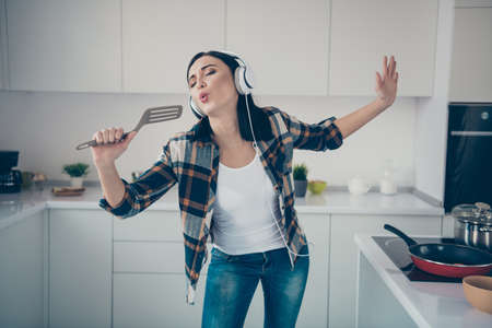 Portrait nice cute lady carefree careless hold hand want scrambled eggs grimace pause break dream pop celebrity shew her denim jeans trendy stylish checkered shirt plaid apartment lips pouted plumpの写真素材