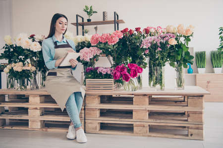 Full length body size view photo of serious focused lady person people use notes look think thoughtful wear blue shirt trendy stylish jeans denim sneakers indoors workplaceの写真素材