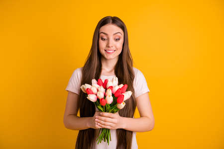 Close up photo of beautiful lady with fresh white  and red tulips. Indicates with her finger to available space for text. 8 march price offer.  Isolated bright yellow background.の写真素材
