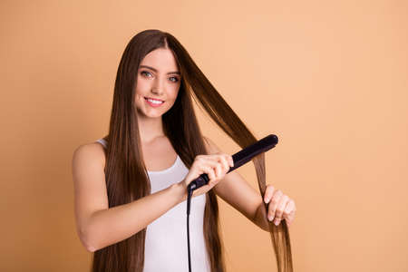 Portrait of nice pretty lovely millennial girl hold hand equipment tool feel confident look have medical treat salon hairstylist isolated beige pastel background dressed light-colored clothingの写真素材