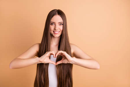 Portrait of cute sweet cute lady make heart want date show love boyfriend have procedures smooth silky hairstyle dressed white top singlet clothes isolated beige background pastelの写真素材
