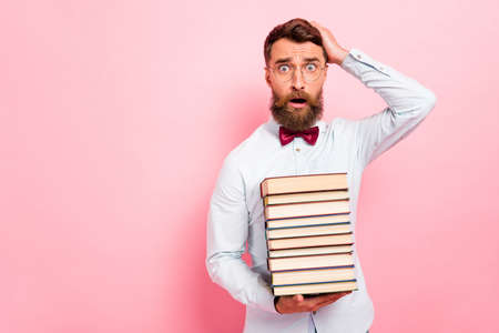 Photo portrait of clever guy holding stack of paper book in hand touching head isolated pastel...