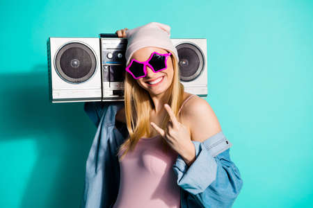 Portrait of nice attractive lovely cute cheerful cheery girl having fun showing horns sign carrying stereo recorder isolated on bright vivid shine blue green turquoise backgroundの写真素材