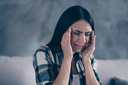 Close up photo beautiful she her lady arm hold temples eyes closed terrible suffer pain displeased grinning hopeless worried wear checkered plaid shirt comfort flat house living room indoorsの写真素材