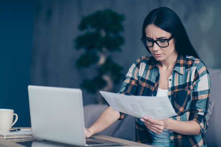 Close up photo amazing beautiful she her lady hand arm hold paper document contract noting notebook table writing data information attentive wear specs checkered plaid shirt house living room indoorsの写真素材
